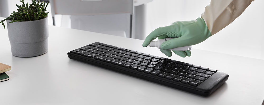 commercial cleaning employee cleaning a computer keyboard